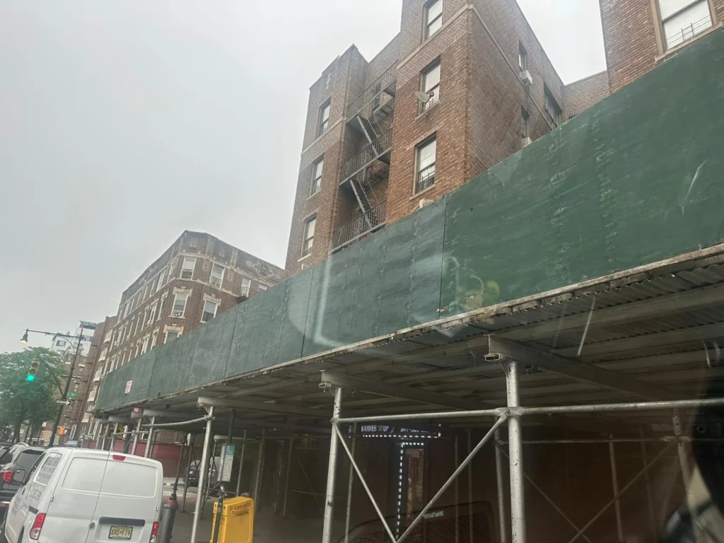 Sidewalk shed scaffolding installed along a brick apartment building in the Bronx, highlighting professional Scaffolding Inspection in Bronx, NY for safety compliance and structural integrity.